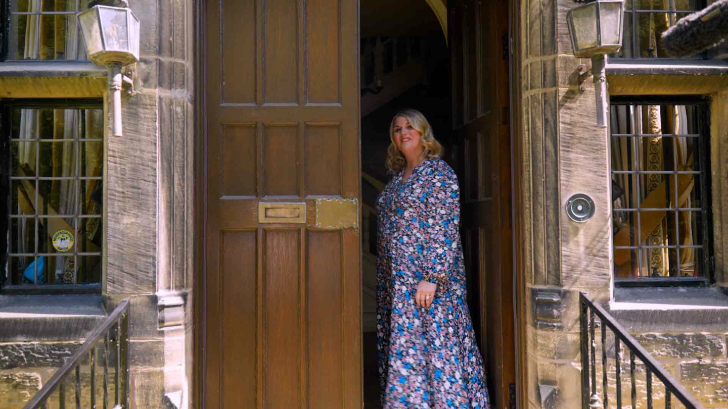 A person wearing a flowery dress stood in a large doorway