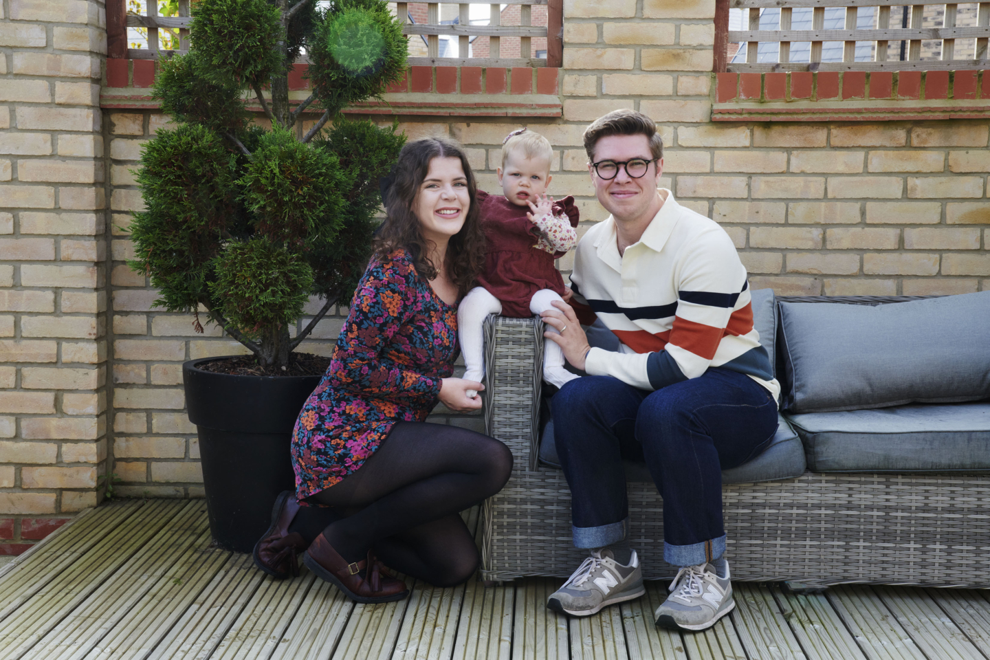 A couple and a baby sitting on outdoor furniture