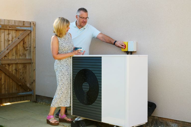 Two people standing next to a heat pump