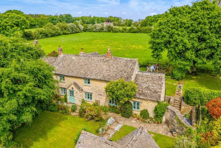 An aerial view of a stone cottage, trees